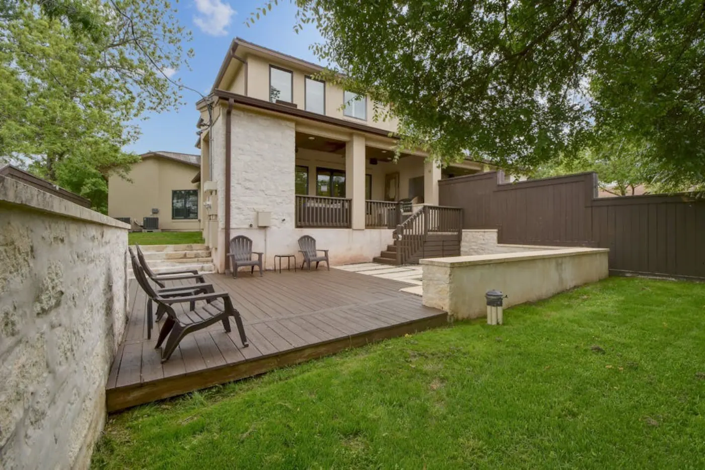 The backyard before the redesign: an empty deck, a patch of lawn and a bare fence