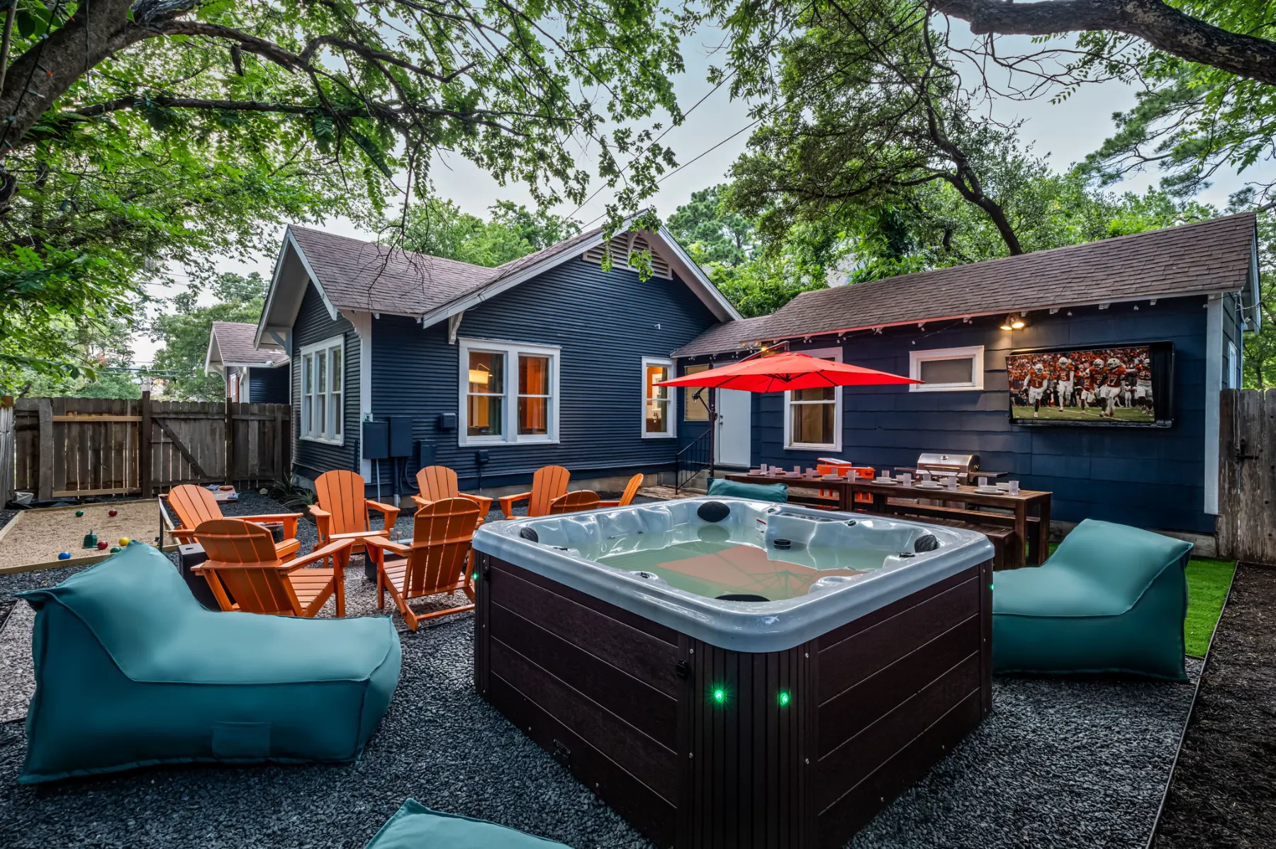 Western Tailgate: a navy bungalow backyard with a hot tub, loungers, a fire pit and an outdoor TV