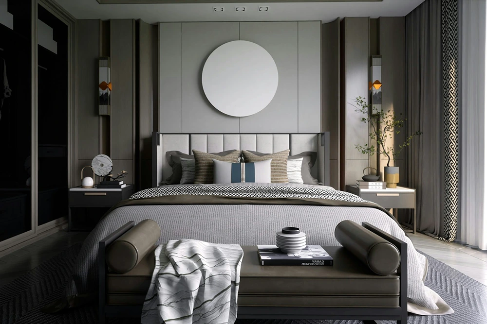 Elegantly designed bedroom with a large bed, grey bedding, and a circular mirror above it. There are nightstands with lamps and plants, mirrored wardrobe doors, patterned curtains, and dark wood flooring.